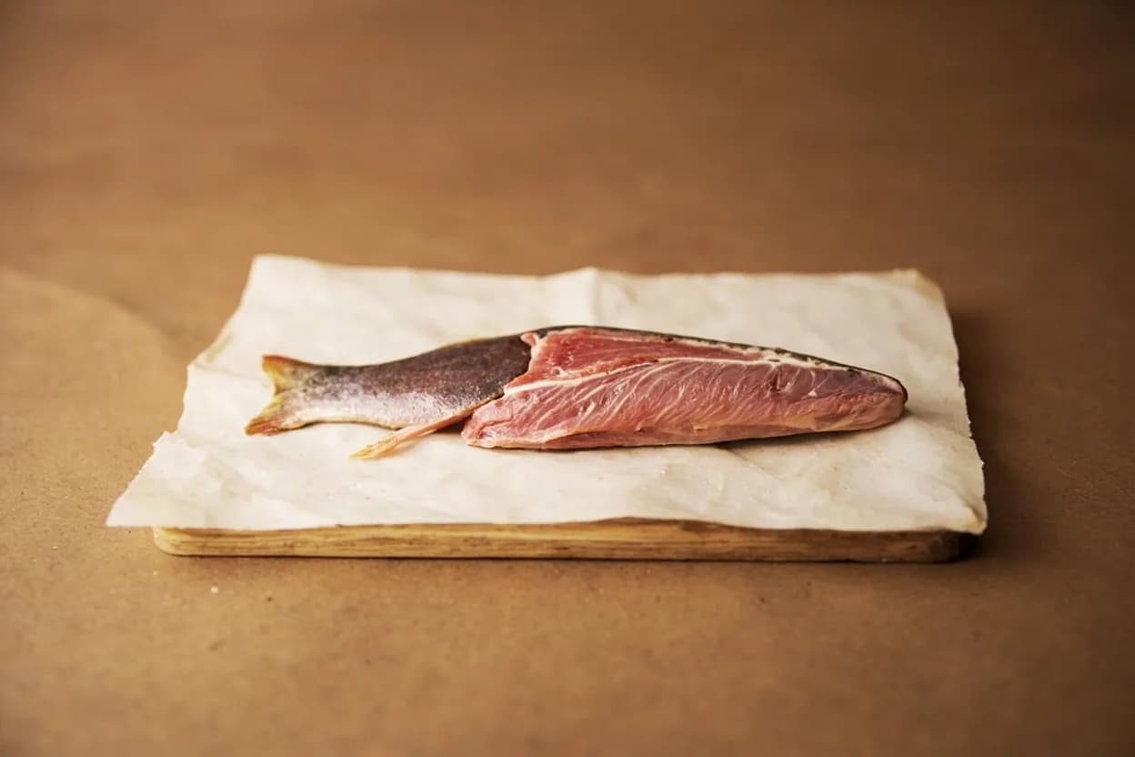 Fish Collar Separation (Coastal East African) in its raw whole-cut form on a butcher's board — The fish collar (the section comprising the pectoral fins, clavicle bones, and the fatty flesh immediately behind the head) is recognized across East African coastal kitchens — particularly in Kenya,… Identifying traits: Rich, fatty meat with a high surface-area-to-volume ratio ideal for charcoal caramelization, Cartilage crisps to a crackling-like texture when grilled at high heat, Contains several distinct muscle groups (cheek-adjacent, pectoral, nape) each with different textures.