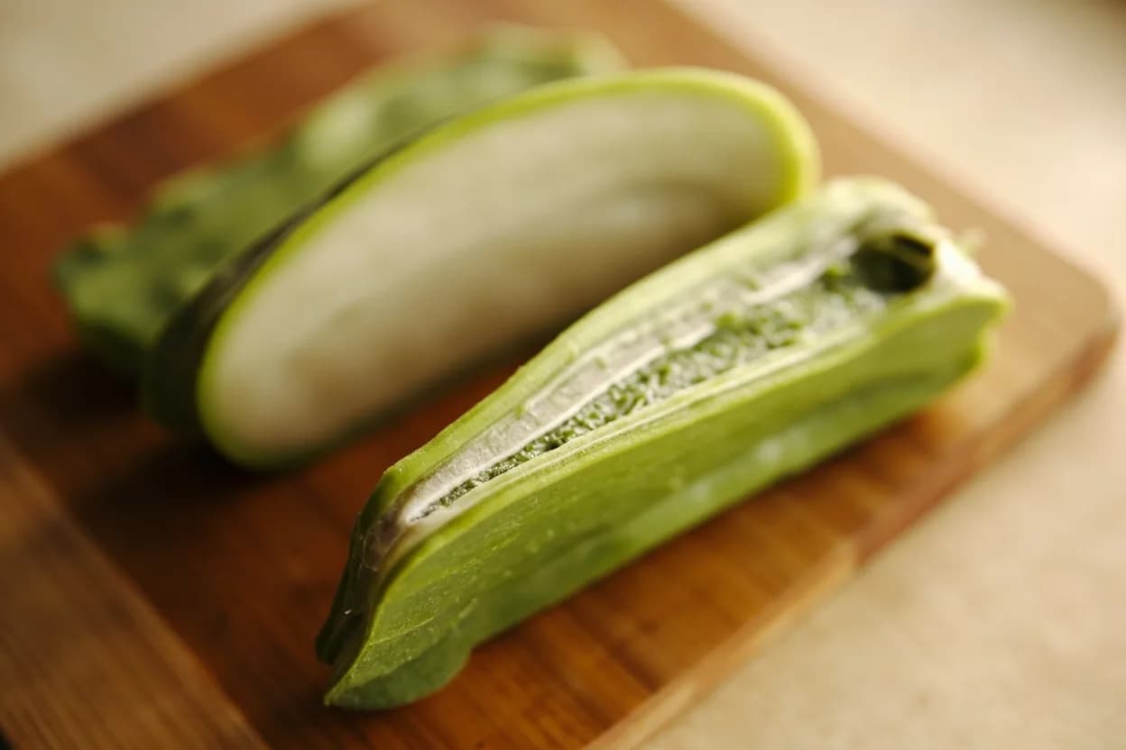 Green Papaya Julienne (Som Tum) in its raw whole-cut form on a butcher's board — The green papaya julienne used in som tum is not a precision French julienne but a deliberately rustic, long-fibre shred produced by a two-step technique: the cook scores the peeled papaya half lengt… Identifying traits: Long, semi-irregular strands that tangle and hold dressing, Crunchy-fibrous texture contrasts with soft tomatoes and peanuts in the salad, Mild, vegetal flavour that acts as a neutral canvas for bold dressings.