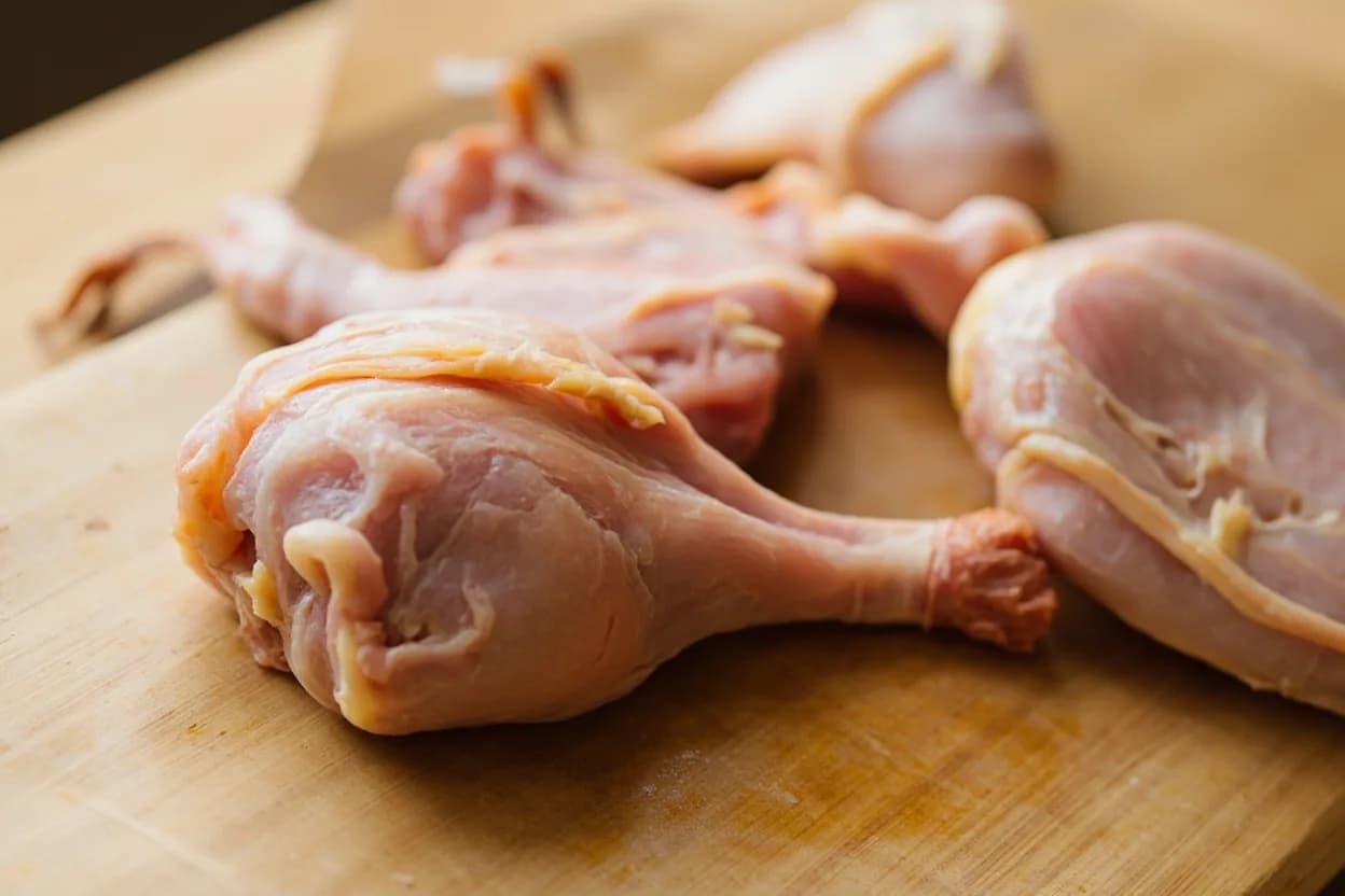 Drumstick & Thigh Separation (Tandoor Prep) in its raw whole-cut form on a butcher's board — Tandoor chicken preparation requires the leg quarter to be separated into its two natural pieces — the thigh (femur section) and the drumstick (tibiotarsus section) — at the knee (stifle) joint, and … Identifying traits: Bone-in throughout — the bone acts as a heat conductor from inside and a natural handle for serving, Scoring (deep parallel cuts to the bone) is mandatory for marinade penetration and even cooking, The thigh and drumstick are cooked as separate pieces to prevent the thin drumstick knuckle from charring before the thick thigh is done.