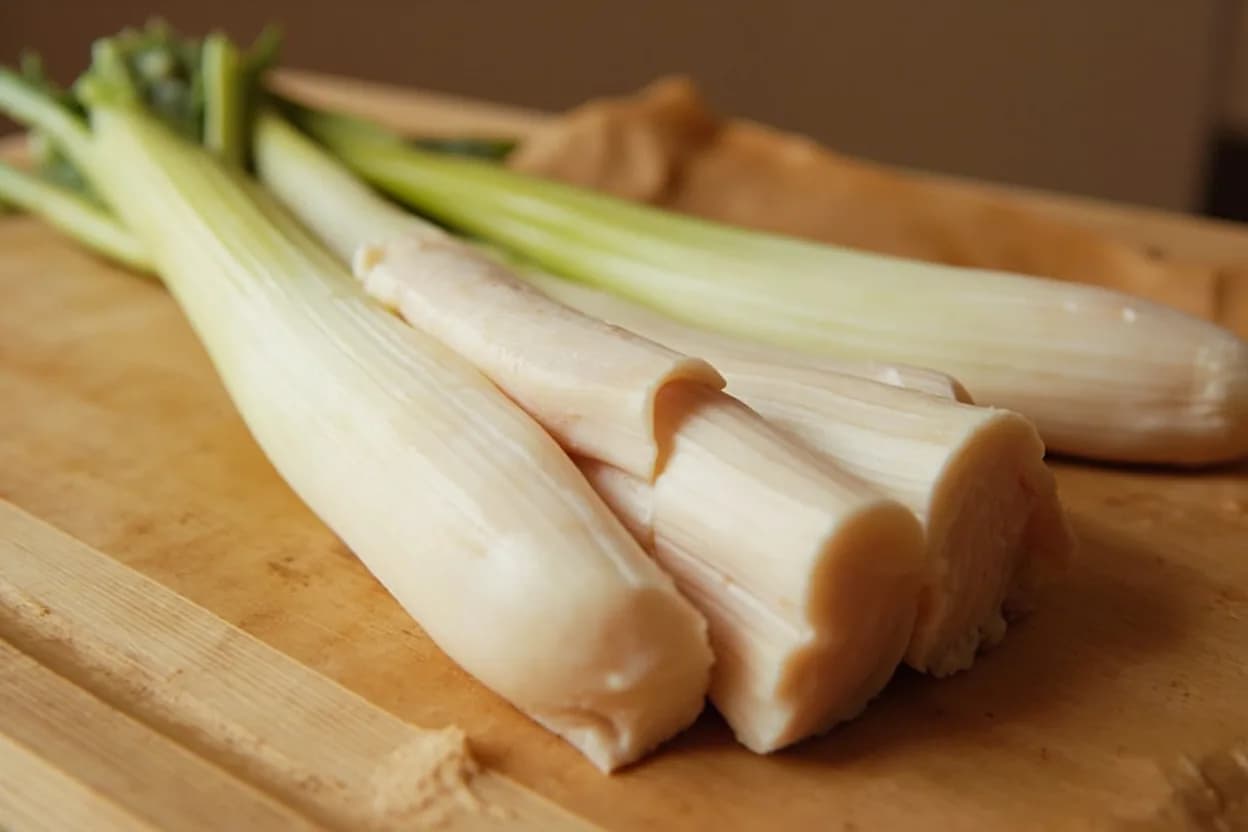 Leek Cleaning & Fine Ring Cut in its raw whole-cut form on a butcher's board — Leek preparation involves two distinct operations: cleaning and cutting. Identifying traits: Concentric layer structure traps grit invisibly — no amount of surface rinsing substitutes for splitting and fanning the layers, The white portion has the highest sugar content and turns jammy and sweet when slow-cooked in butter, Fine rings (2–3 mm) remain semi-distinct in vinaigrettes and garnishes; medium rings (5–8 mm) dissolve at the edges into soups and braises.