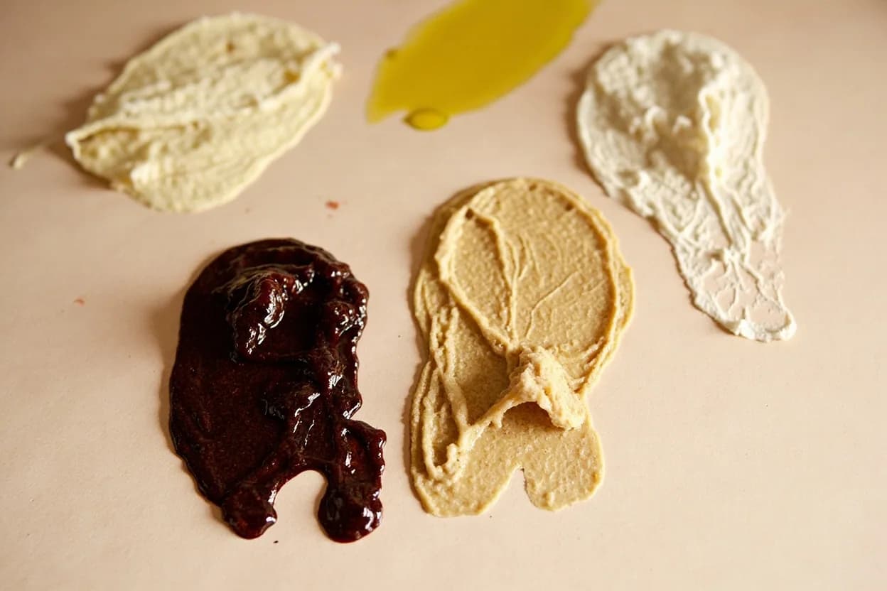 Grape Molasses (Dibs Enab) paired with Tahini (Lebanese / Palestinian / Syrian) — the canonical affinity made visible. Dibs wa tahini — grape molasses drizzled over tahini — is one of the oldest Levantine breakfast combinations; the sesame paste's bitter, nutty fat absorbs the grape sweetness into a caramel-like spread.