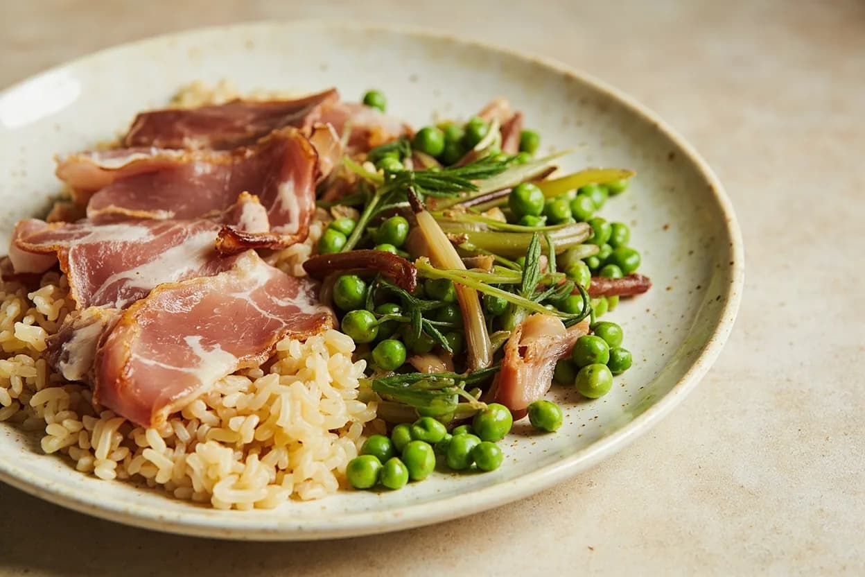 Pancetta paired with Risotto (peas, asparagus, radicchio) (Venetian/Northern Italian) — the canonical affinity made visible. Pancetta lardons rendered at the start of a risotto — especially risi e bisi — lay down a savoury-fat base that enriches the stock as it is ladled in; peas and asparagus provide contrast sweetness.
